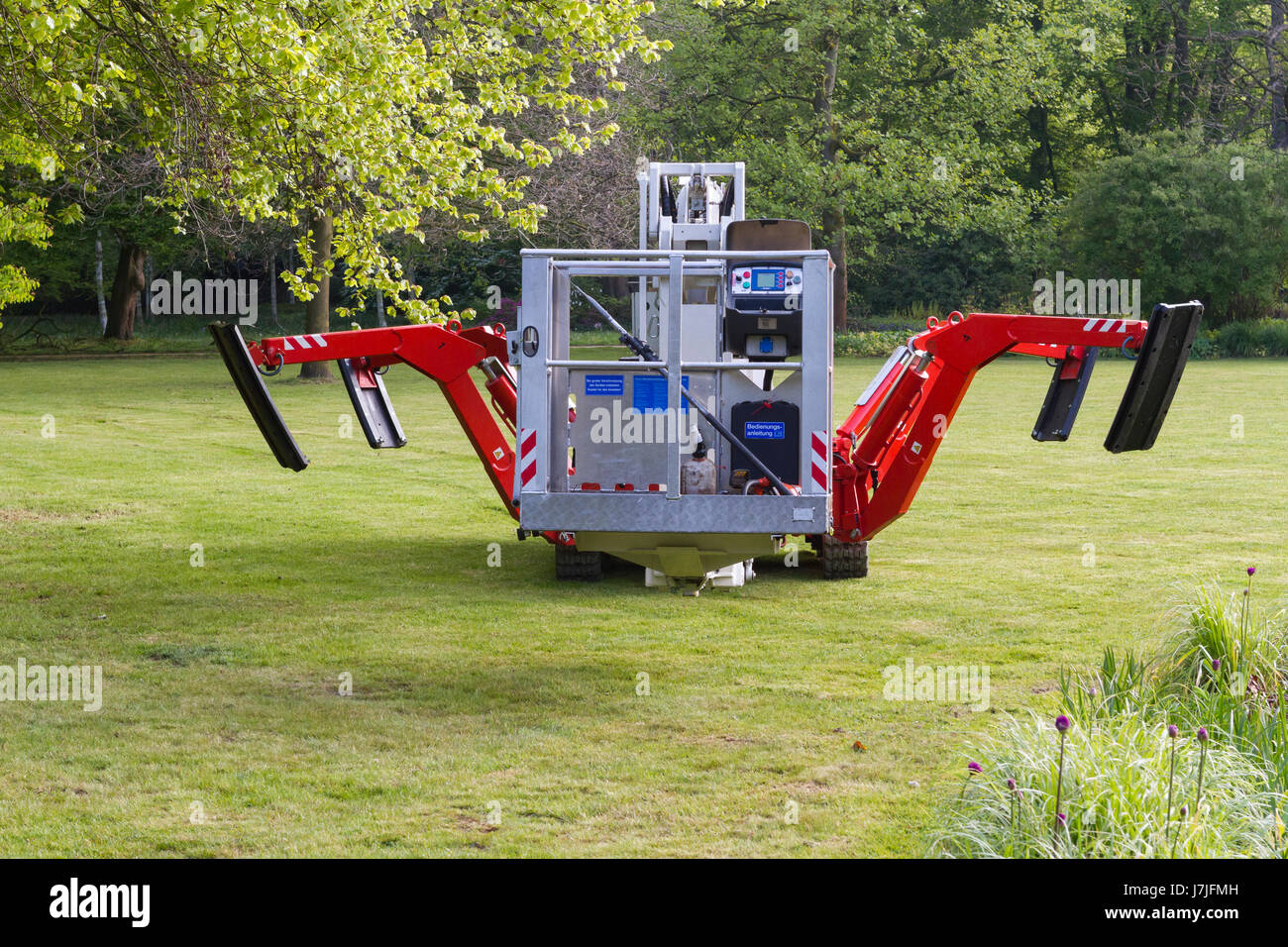 Selbstfahrende Hubarbeitsbühne mit ausziehbaren Beinen und Caterpillar tracks verwendet wird, um Zweige von den Bäumen geschnitten Stockfoto