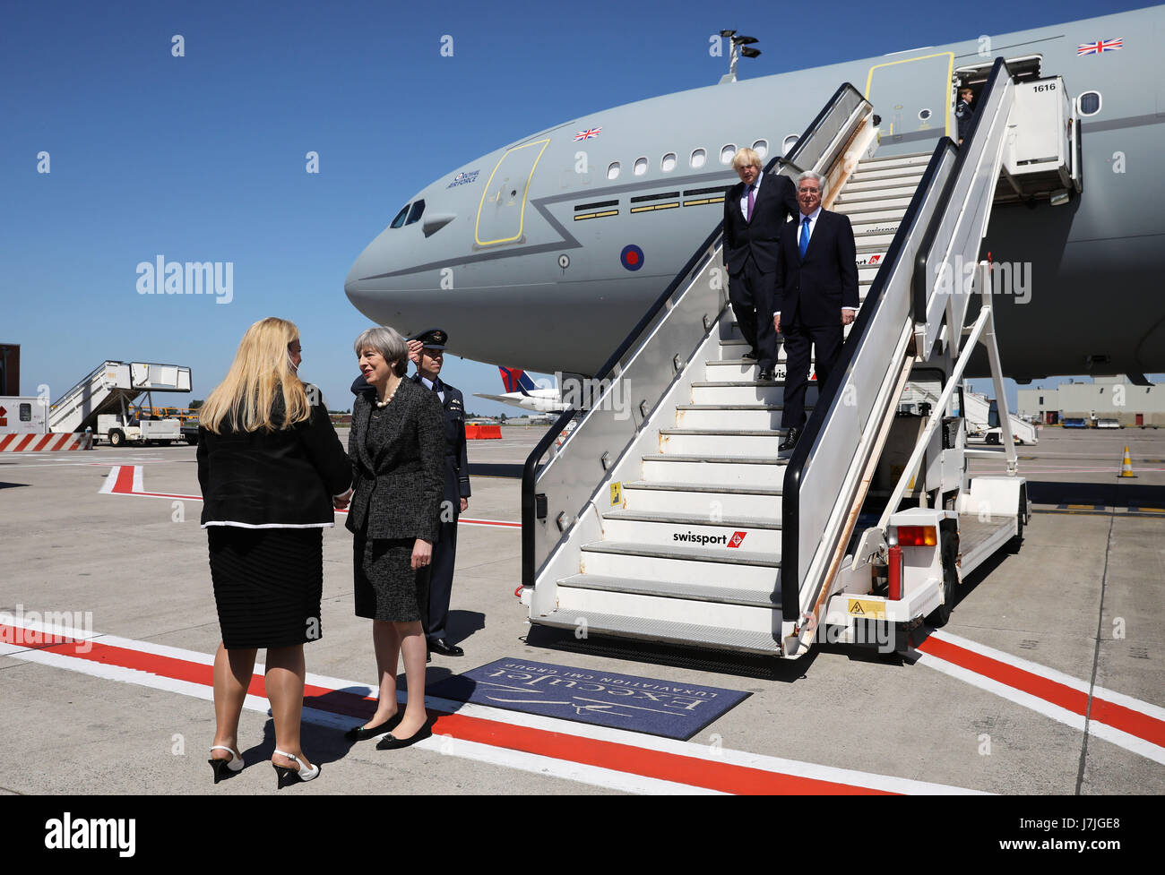 Ständiger Vertreter bei der NATO, Sarah MacIntosh CMG grüßt Premierminister Theresa May, als sie mit Defence Secretary Sir Michael Fallon und Außenminister Boris Johnson am Abelag Flughafen in der Nähe von Brüssel, Belgien, ankommt bevor sie die North Atlantic Treaty Organisation (NATO)-Gipfel in der Stadt teilnehmen. Stockfoto