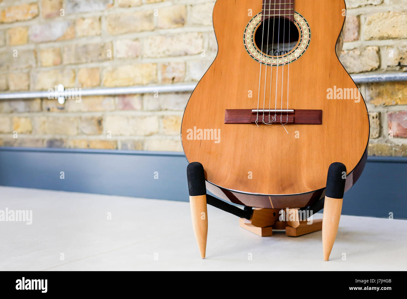 6-saitigen Gitarre auf einem Ständer, gegen innere Mauer mit industrielle elektrische Leitung Stockfoto