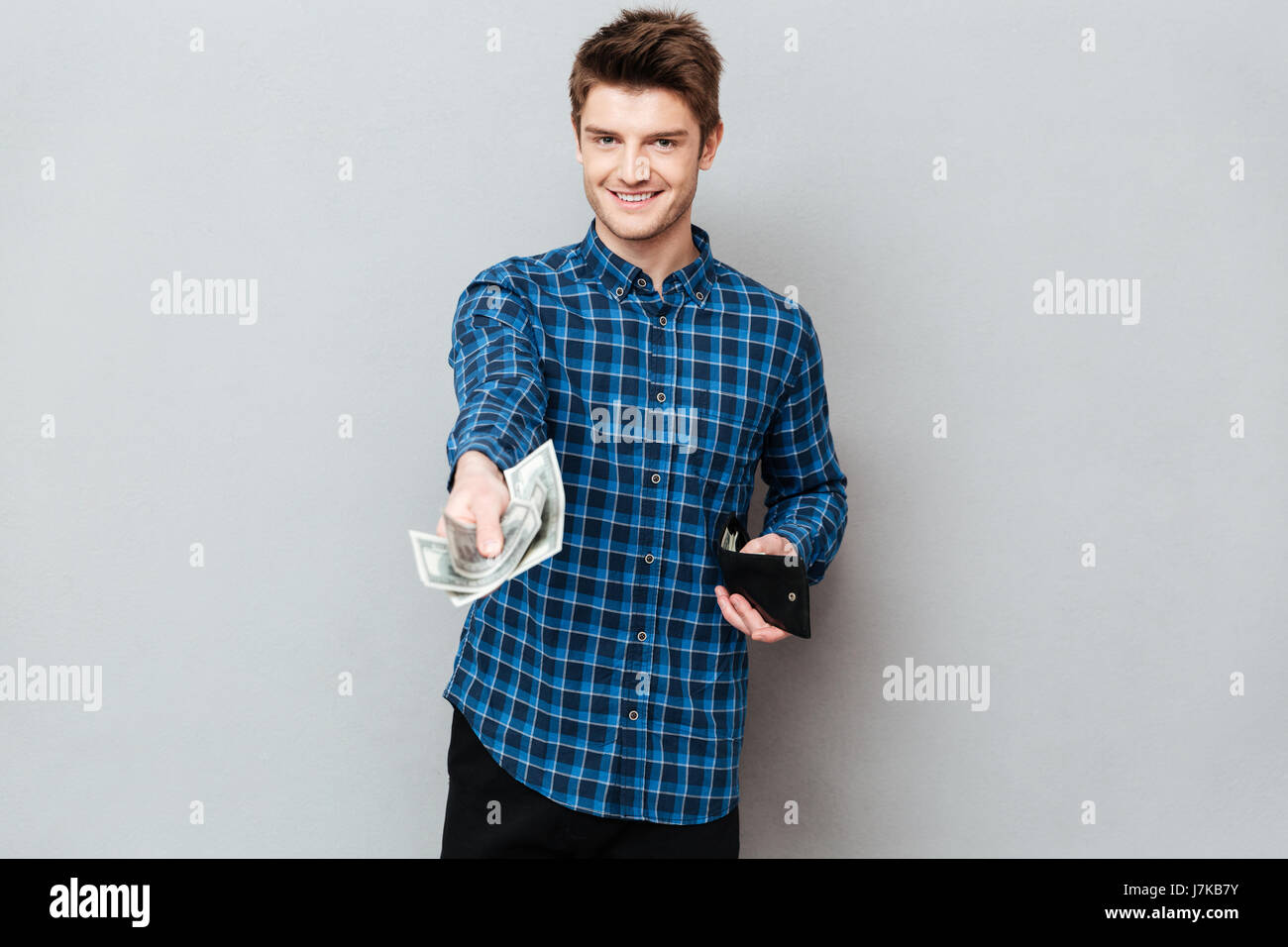 Schönen jungen Mann geben Bargeld Fron Brieftasche, Kamera, isoliert Stockfoto