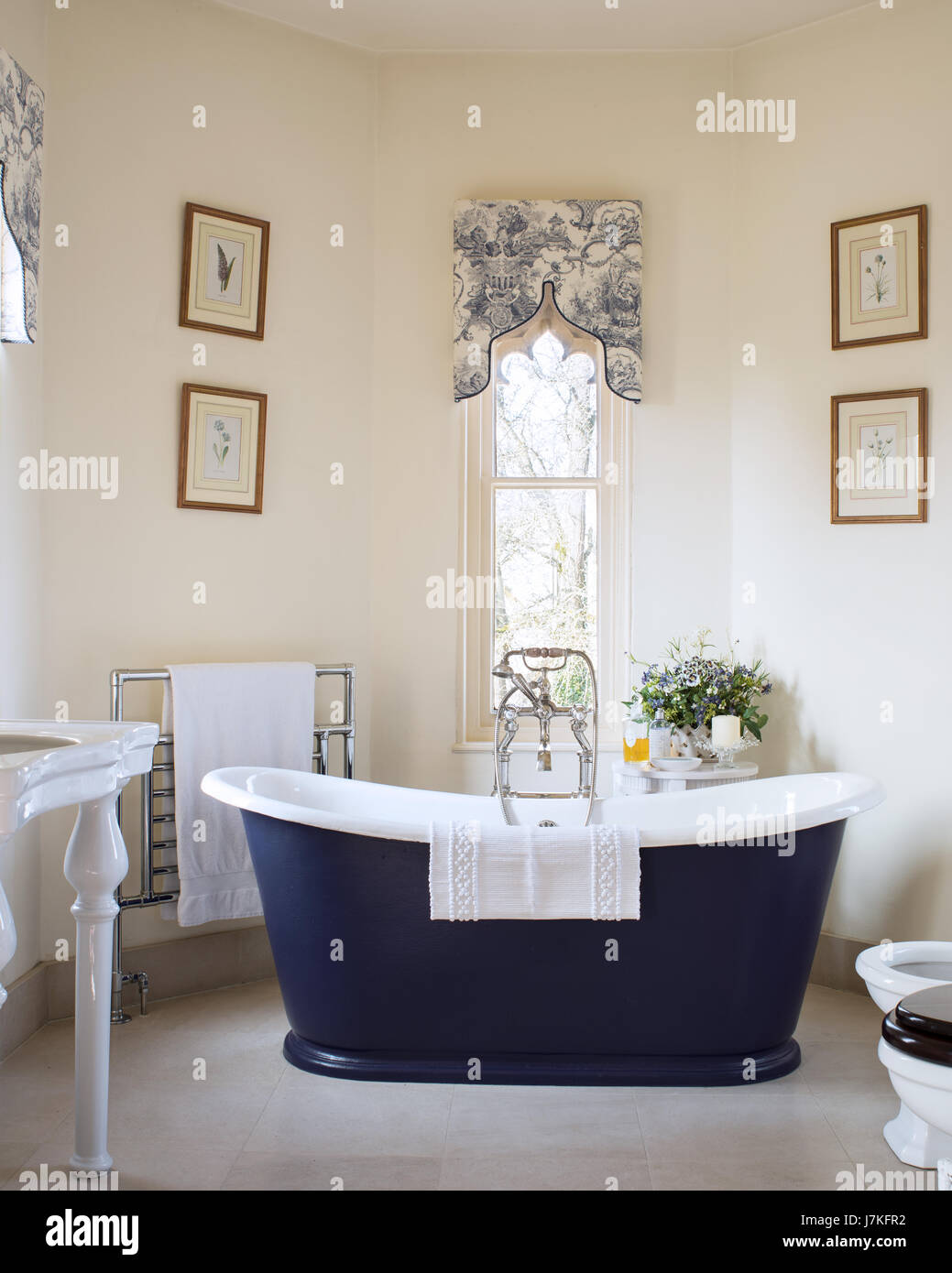 Dunkel blau freistehende Badewanne im Zimmer mit gotischen Fenstern und Toile De Jouy Muster Schabracken Stockfoto
