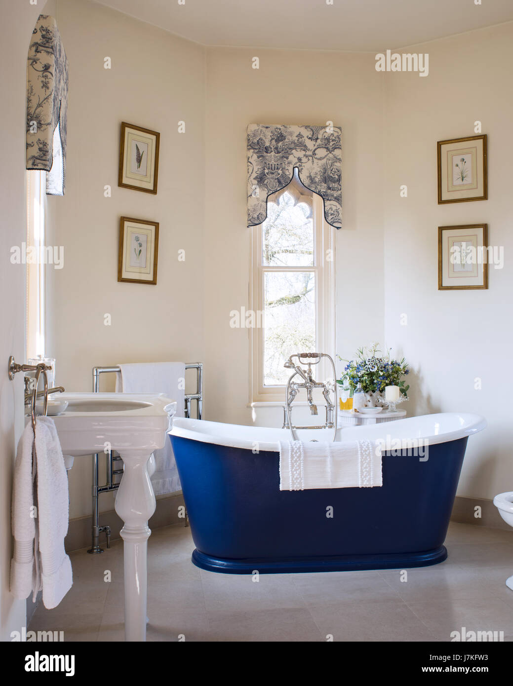 Dunkel blau freistehende Badewanne im Zimmer mit gotischen Fenstern und Toile De Jouy Muster Schabracken Stockfoto