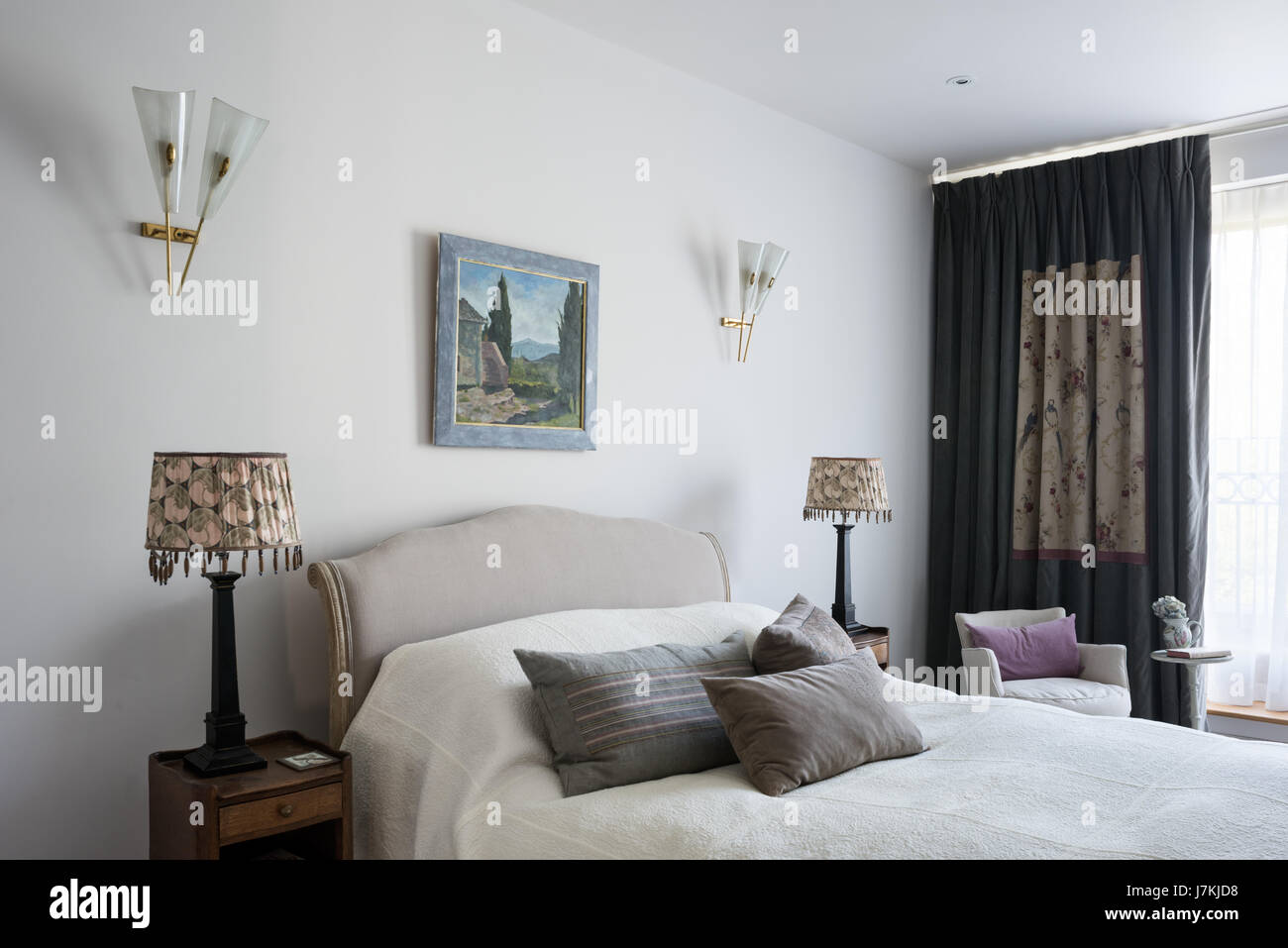 Gästeschlafzimmer mit Art-déco-Stil Wandleuchten und antiken Vorhangstoff Stockfoto