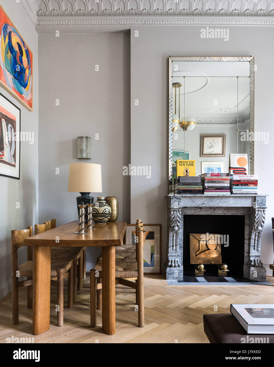 Holztisch und Stühle von Charlotte Perriand mit 1940er Jahre Spiegel über französische graue Marmor-Kamin Stockfoto