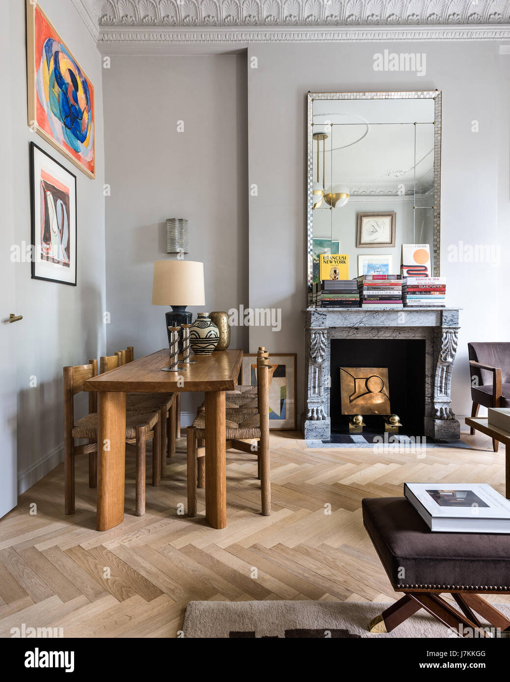 Holztisch und Stühle von Charlotte Perriand mit 1940er Jahre Spiegel über französische graue Marmor-Kamin Stockfoto