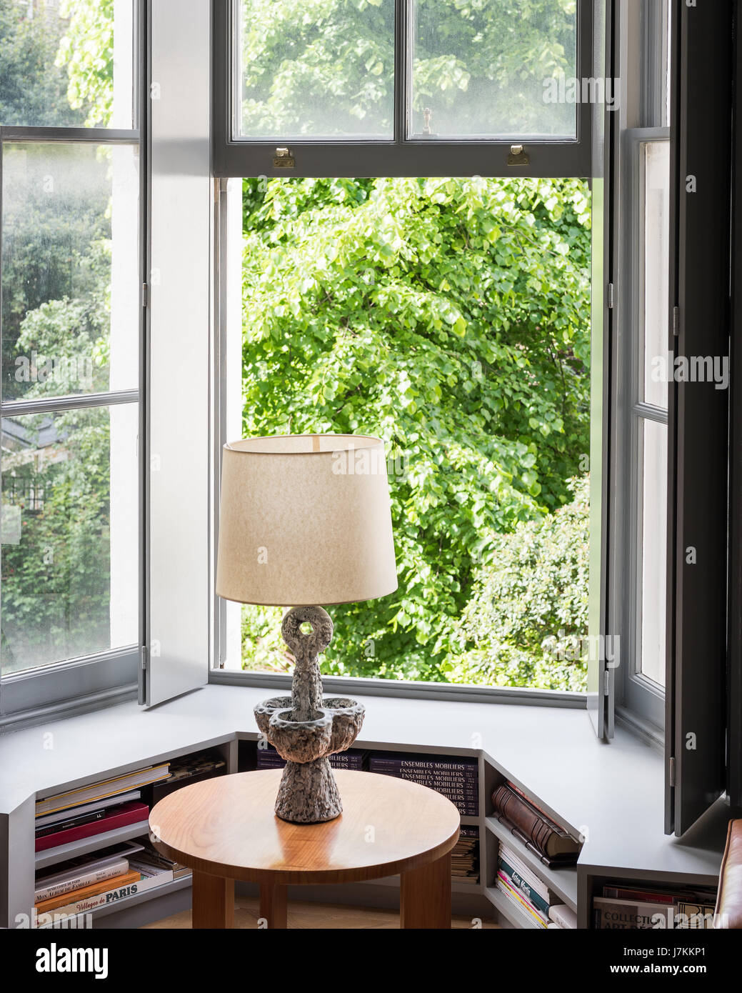 Lampe auf Tisch am Fenster mit Sitz in ruhigen grauen Tönen gemalt Stockfoto