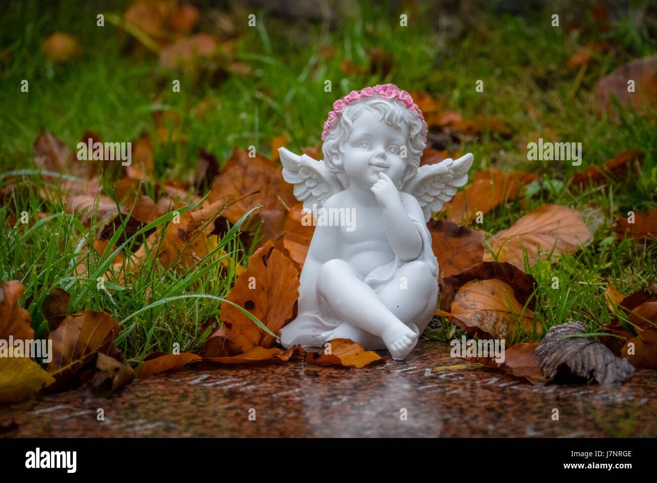 Kleine Engelsfigur neben einem Kind Grab im Friedhof Stockfoto