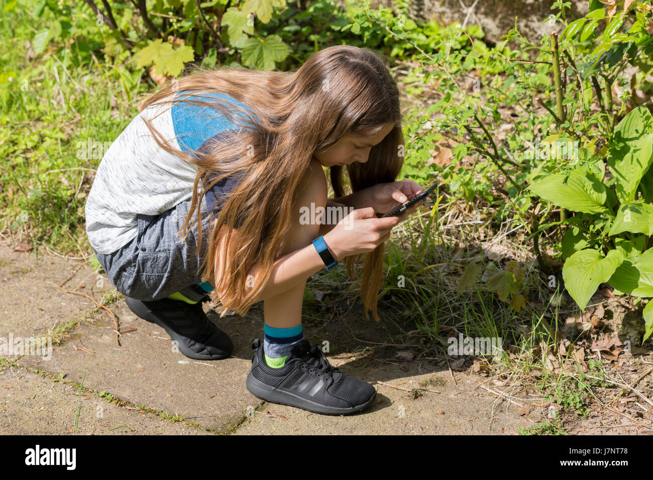 Ein Mädchen mit Kamera auf Touchscreen-Handy / Smartphone zu Bilder / Fotos / Fotos im Garten außerhalb Stockfoto