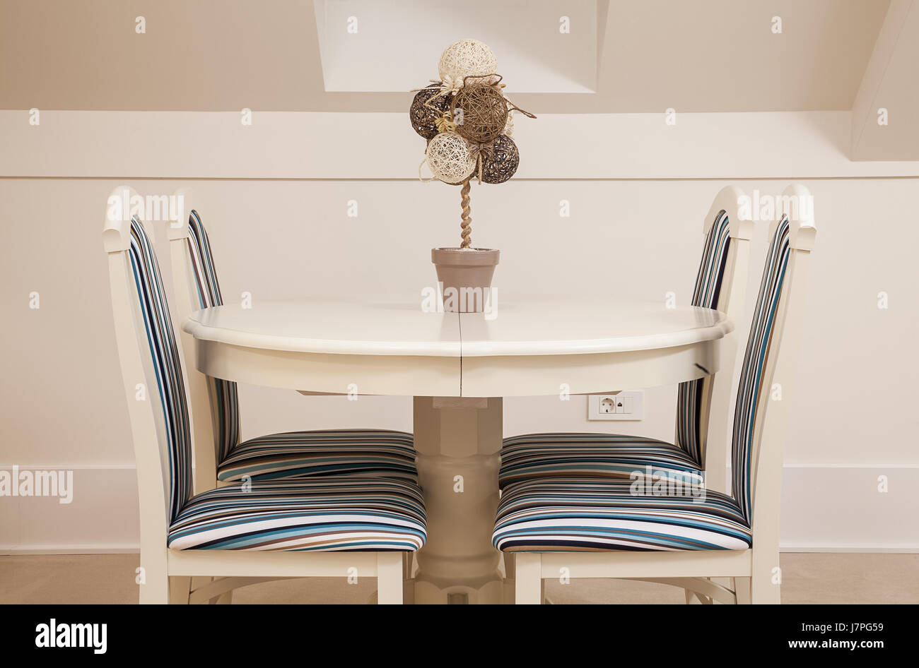 Moderne weiße Holzmöbel, Festlegen von stilistischen Stühlen und runder Tisch, dekoriert mit künstlichen Blumen. Stockfoto