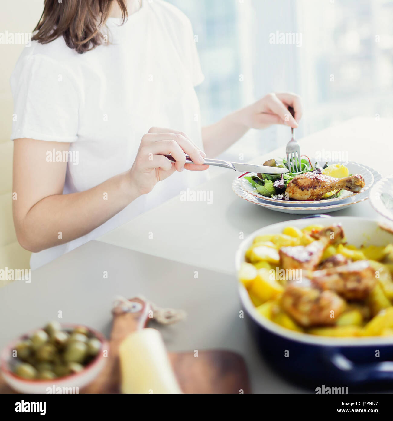 Nahaufnahme der Frau beim Abendessen mit gerösteten Chiken mit Kartoffeln serviert mit Blattsalat Stockfoto