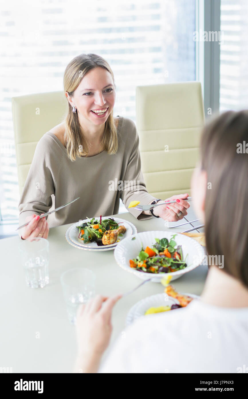 Lächelnde Frauen gemeinsam am Tisch essen Stockfoto