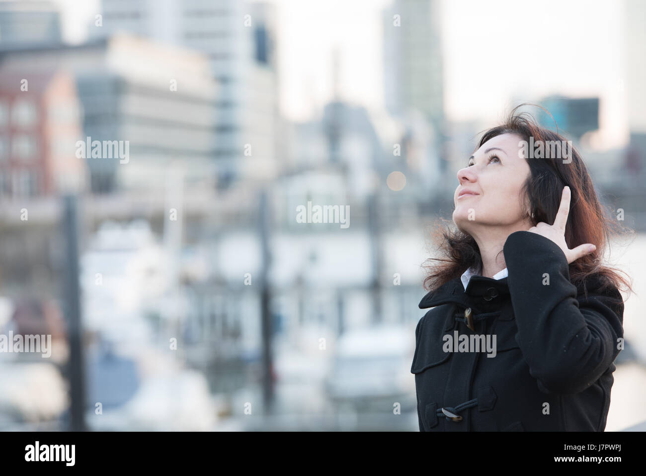 glücklich lächelnde Frau in schwarzer Mantel im Hafen Stockfoto