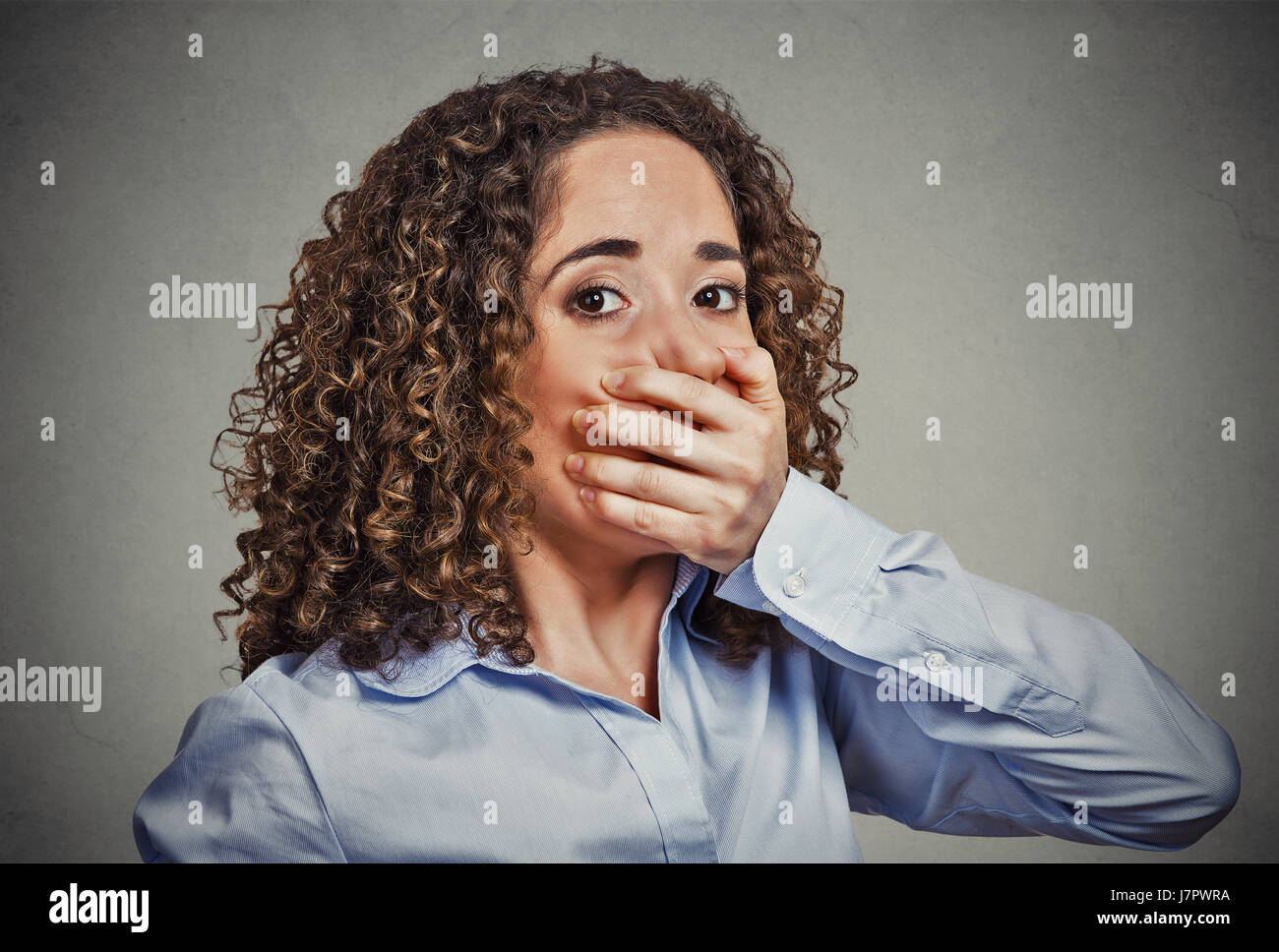 Porträt von Angst junge Frau den Mund mit der Hand ihr auf graue Wand Hintergrund isoliert Stockfoto