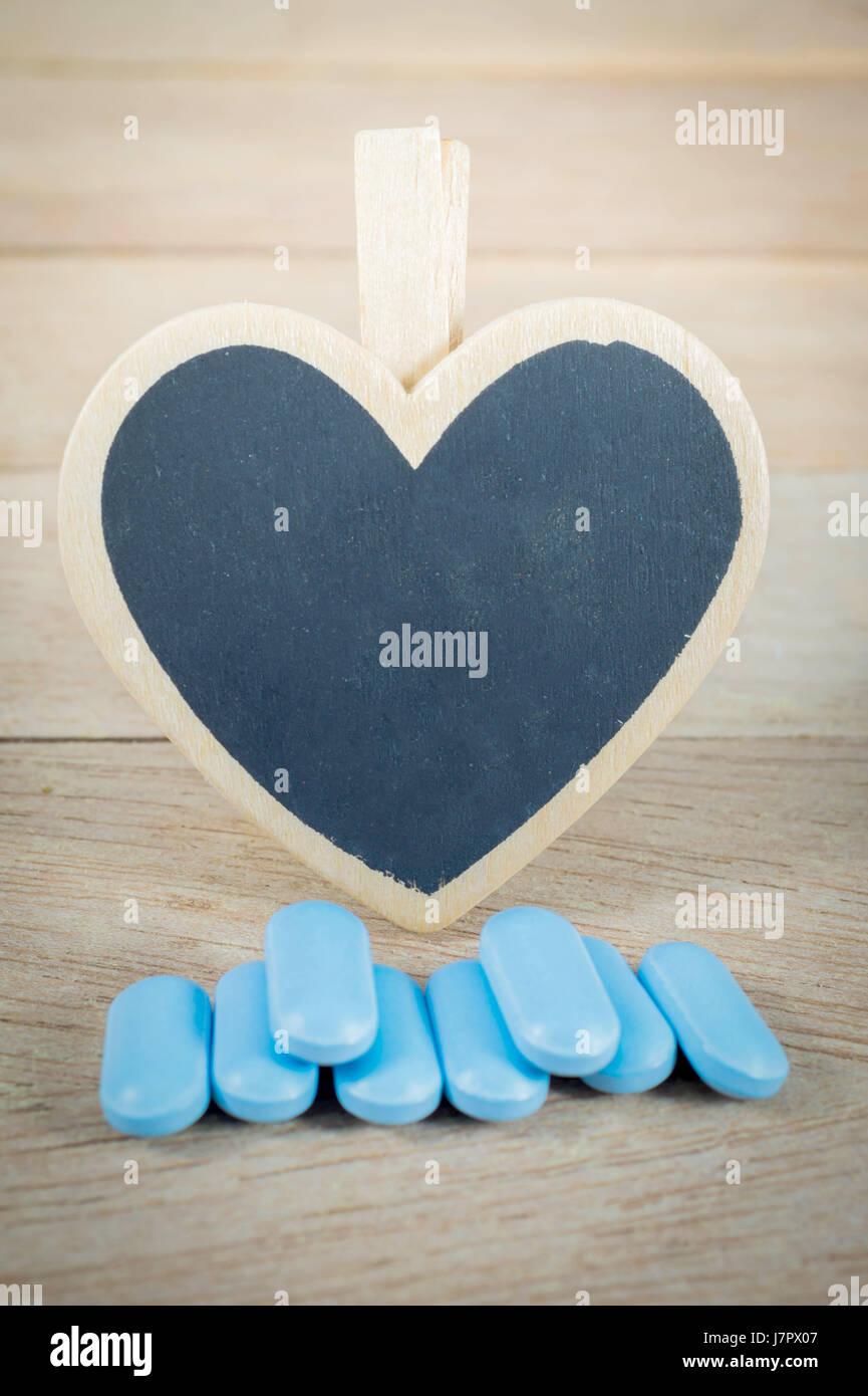 Blaue Pillen mit leeren Herzen Form Tafel auf Holz Hintergrund Stockfoto