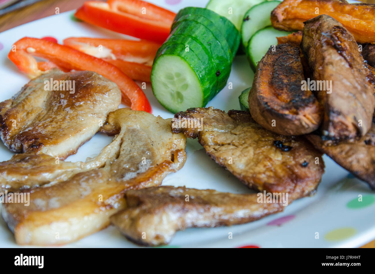 Gebratene Schweinelende Koteletts mit gebackene Süßkartoffel Wedges, in Scheiben geschnitten, Paprika und Gurken. Stockfoto