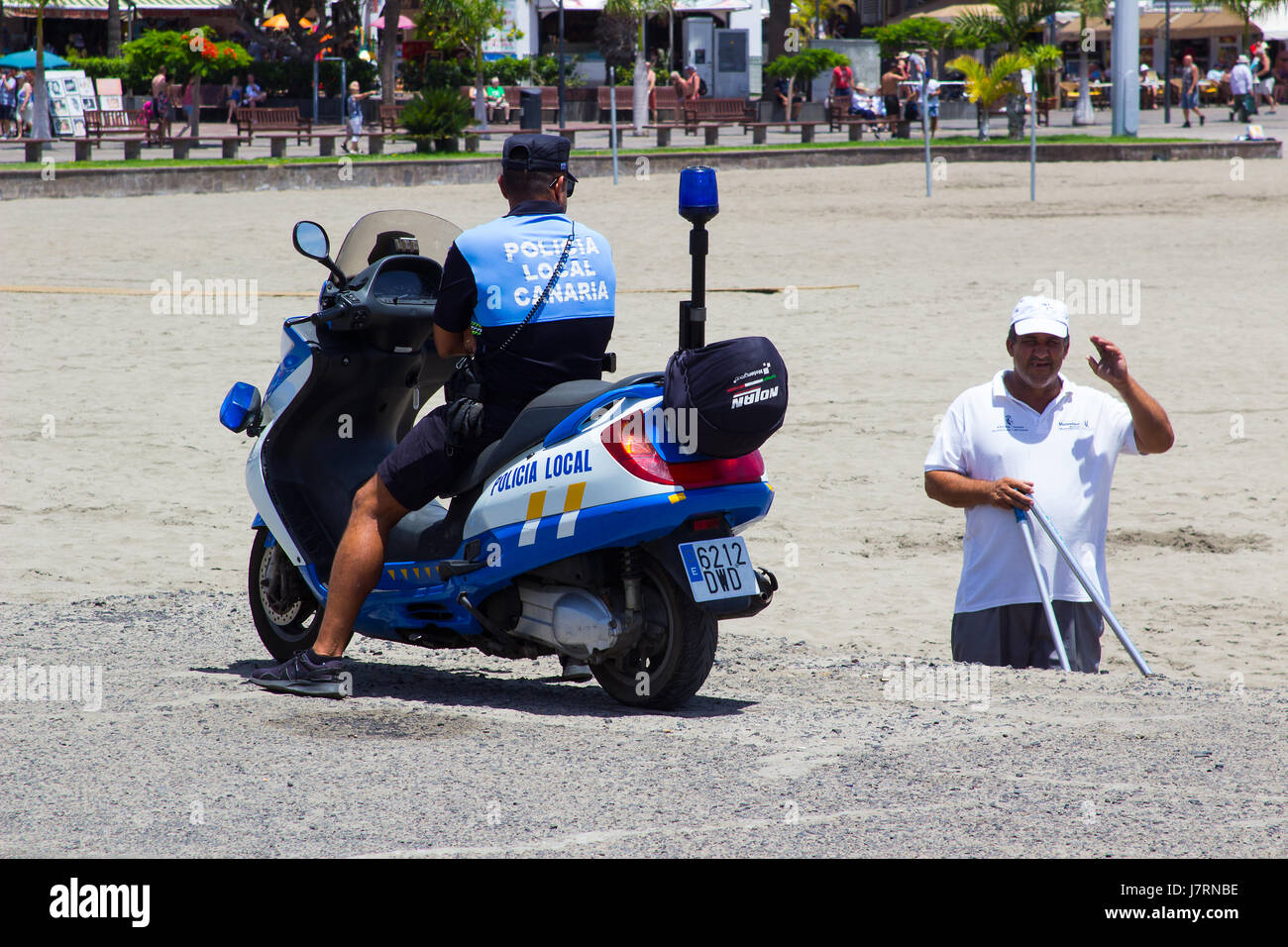 Kanaren Polizist auf einem Motorroller nimmt sich Zeit, mit einem älteren zivilen Mann in Los Cristianos in Teneriffa zu chatten Stockfoto