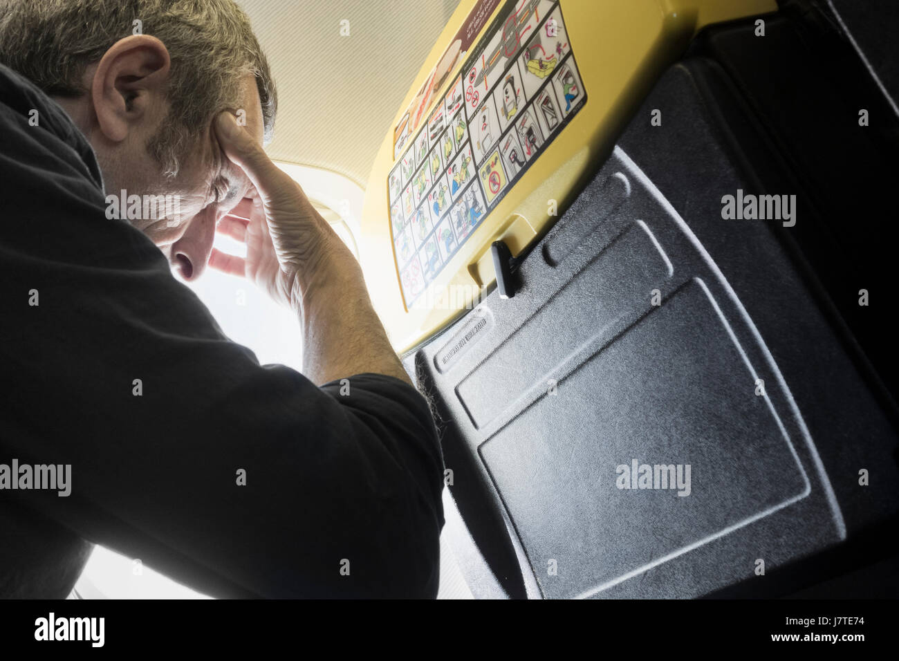 Ryanair.Mature Mann, der versucht in Fensterplatz auf Ryanair-Flug schlafen. Stockfoto