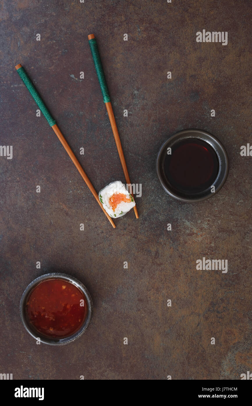 Vietnamesische Reispapier-Rolle. Minimalistische Komposition von Sushi-Rolle, Stäbchen, Chili und Sojasauce. Ansicht von oben, Leerzeichen Stockfoto