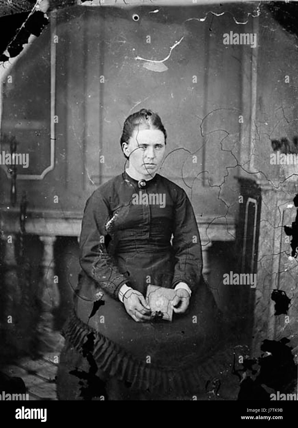 Dieses Bild zeigt eine Frau, die in einer ruhigen und reflektierenden Haltung sitzt, möglicherweise in einem Haus oder im Freien. Stockfoto