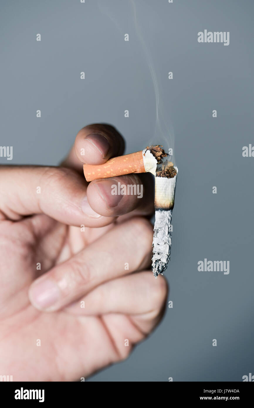 Closeup von einem kaukasischen Jüngling mit einem gebrochenen brennenden Zigarette in der hand Stockfoto Closeup von einem kaukasischen Jüngling mit einem gebrochenen brennenden Zigarette in der hand Stockfoto