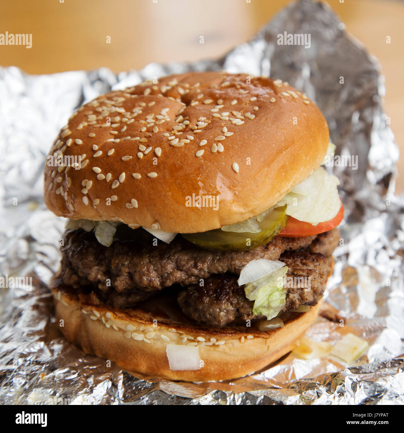 Ein Beefburger wird in einem bestreute Brötchen serviert. Sesam oben das Brot Brötchen. Stockfoto