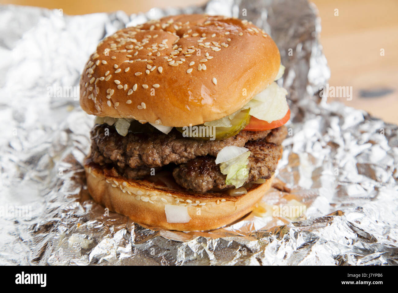 Ein Beefburger wird in einem bestreute Brötchen serviert. Sesam oben das Brot Brötchen. Stockfoto