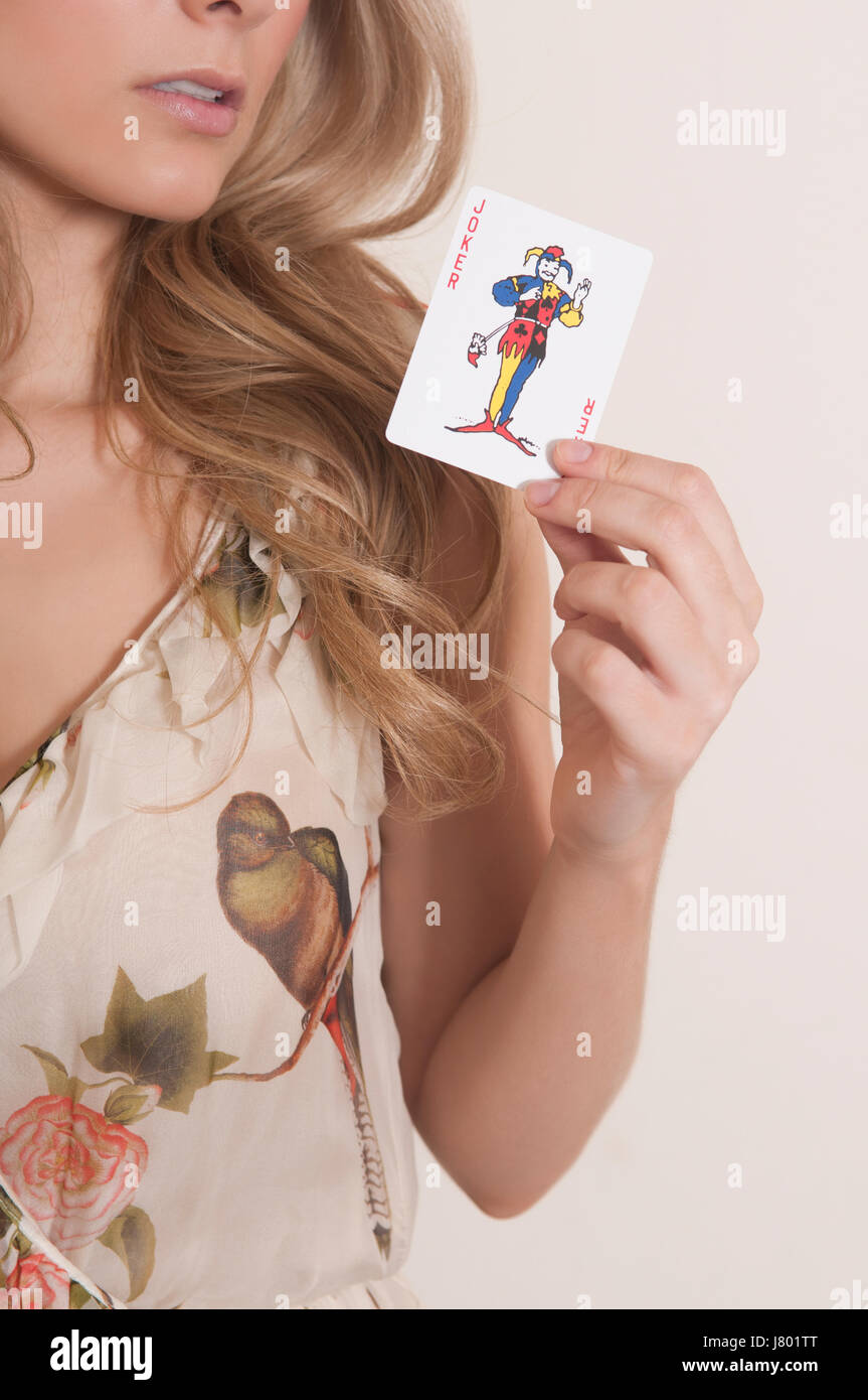 Frau hält eine Spielkarte jocker Stockfoto