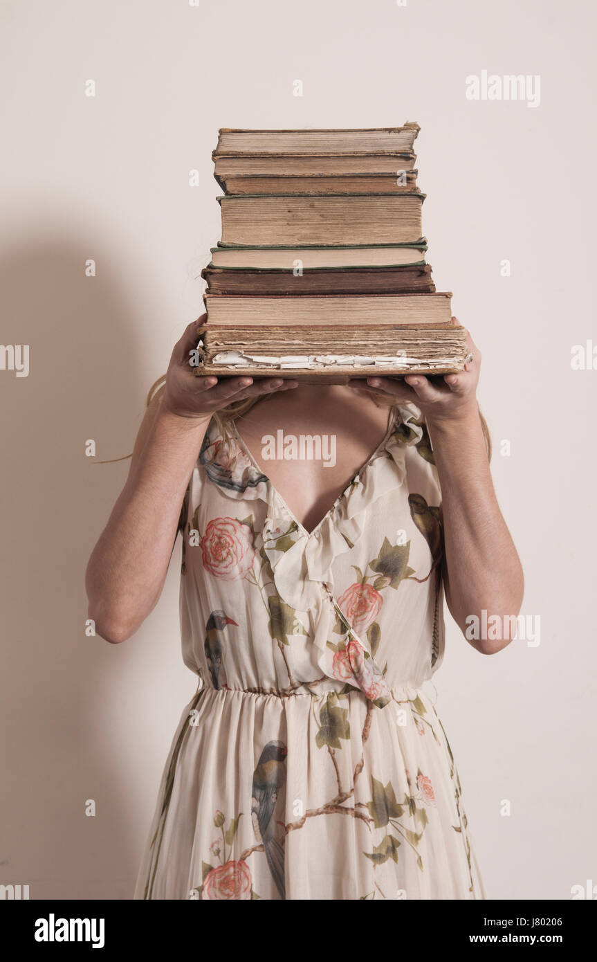Junge Frau mit einem Haufen von alten Büchern Stockfoto