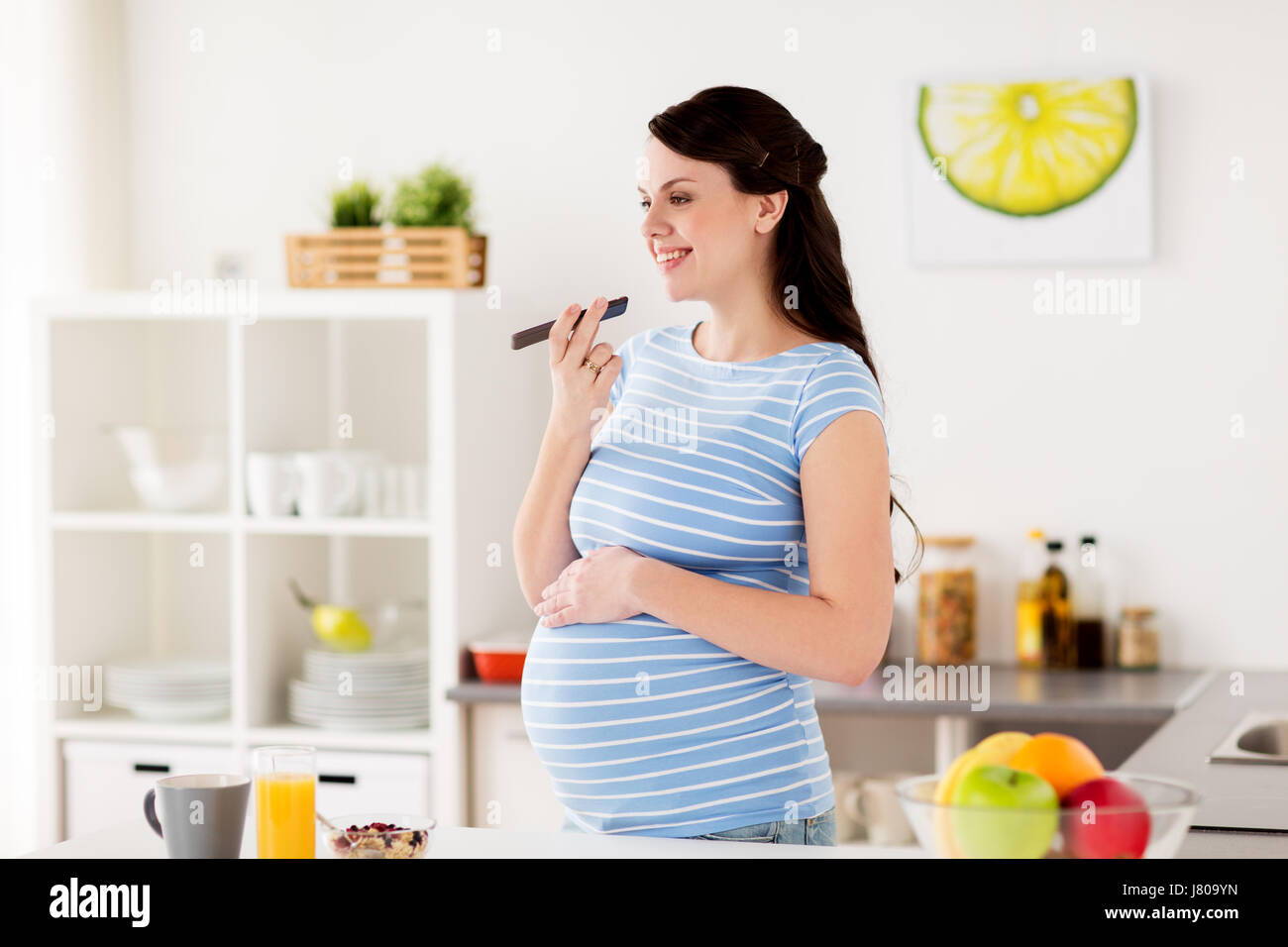 glücklich schwanger Frau mit Smartphone zu Hause Stockfoto