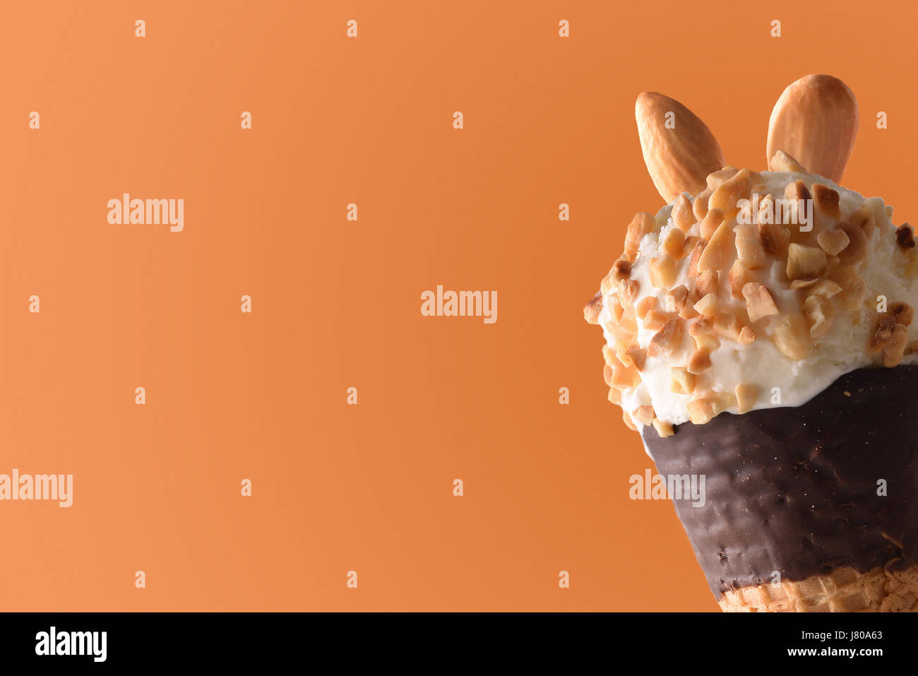 Ice Cream Cone aromatisierte Sahne Mandel hautnah. Garniert mit kleinen Stücken von Mandeln. Mit orangem Hintergrund. Horizontale Komposition. Stockfoto