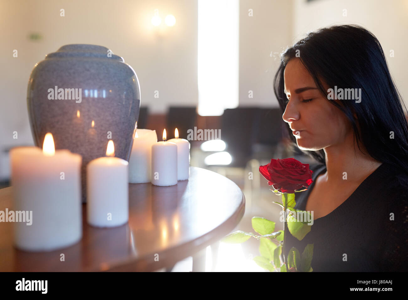 Frau mit rose und Grabbeigaben Urn in der Kirche Stockfoto