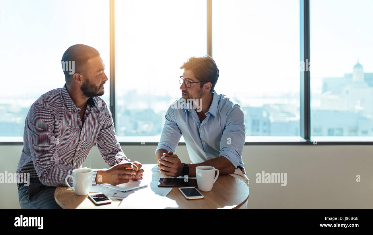 Zwei Geschäftsleute sitzen auf einem Couchtisch und geschäftliche Angelegenheiten zu diskutieren. Führungskräfte arbeiten in ihrem Büro. Stockfoto