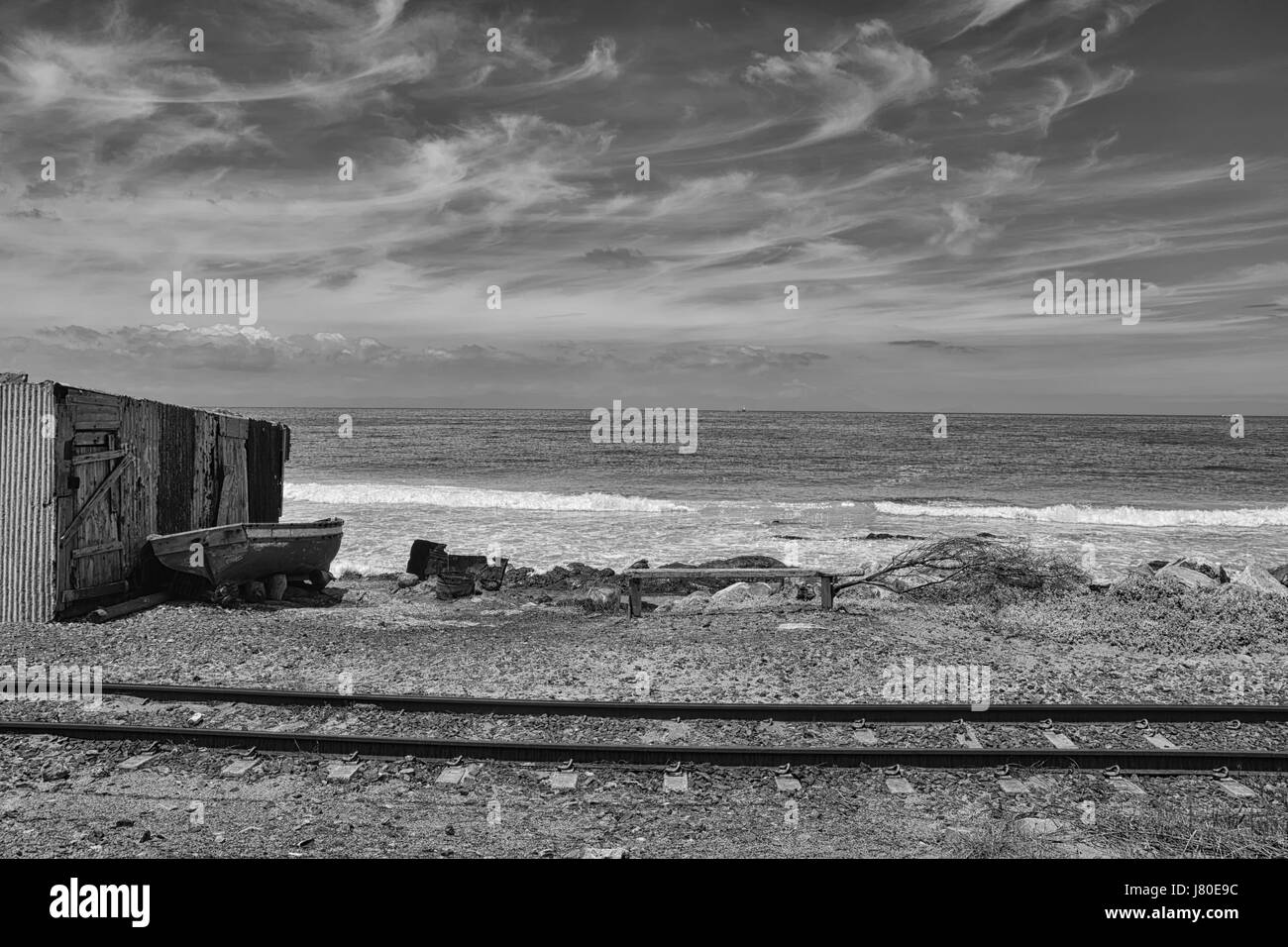 Entlang des Strandes verläuft eine Bahnlinie auf False Bay, Südafrika Stockfoto