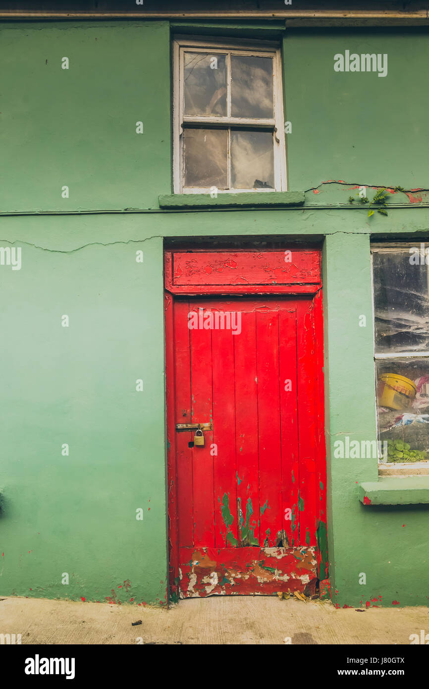 eine rote Tür mit grünen Wänden mit einige sichtbare Risse auf. Stockfoto