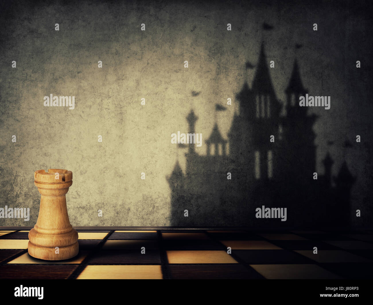 Turm Schachfigur wirft einen Schatten in Form eines Schlosses auf eine Betonwand. Unternehmen streben. Magische Verwandlung. Stockfoto