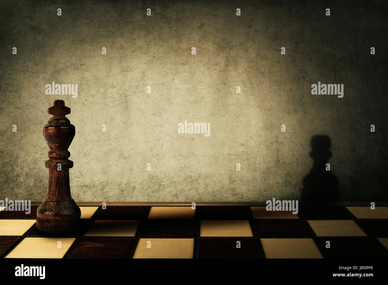 König Schachfigur wirft einen Schatten eines Bauern auf eine Betonwand. Komplex und Misswirtschaft Konzept. Magische Verwandlung. Stockfoto