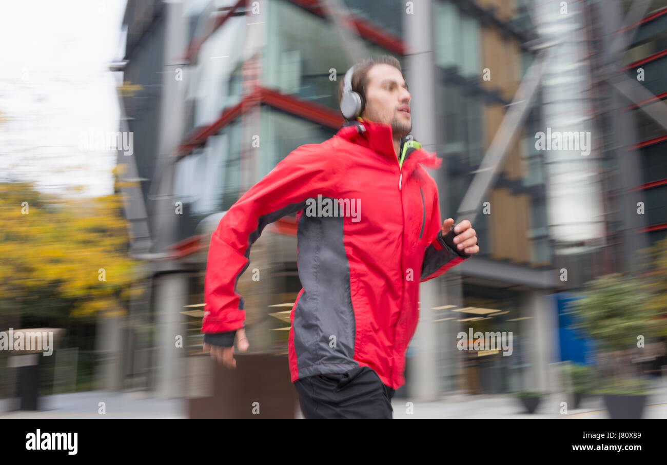 Mann mit Kopfhörern städtische Gebäude vorbei läuft Stockfoto