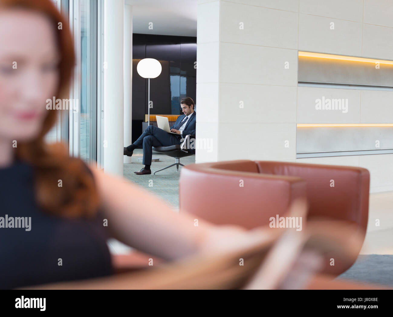 Geschäftsleute mit Laptop und Zeitunglesen in lounge Stockfoto