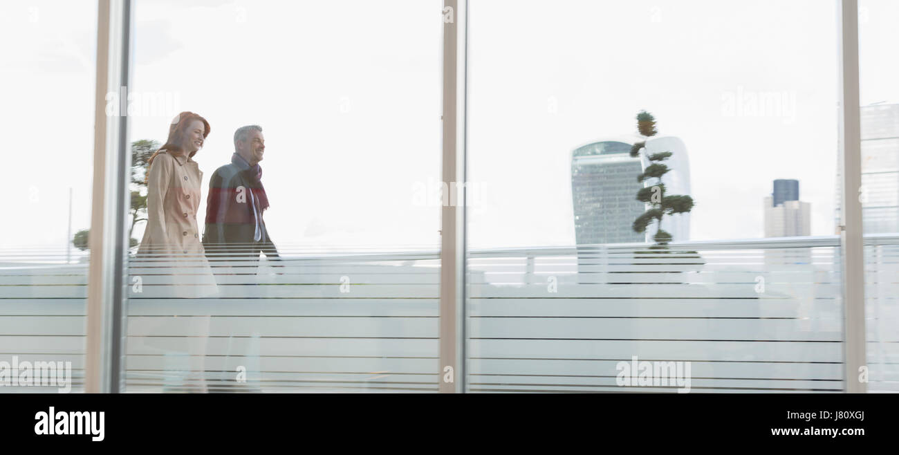 Unternehmer und Unternehmerin zu Fuß auf städtischen Hochhaus-Balkon Stockfoto