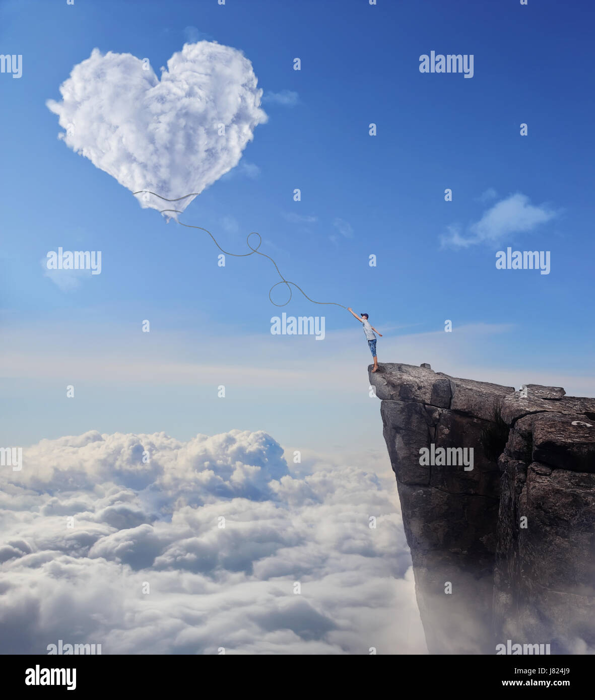 Imaginäre Sicht mit einem jungen am Rande einer Klippe, versucht, ein Herz zu fangen geformt Cloud mit einem langen Seil. Folgen Sie Ihrem Herzen-Konzept. Stockfoto
