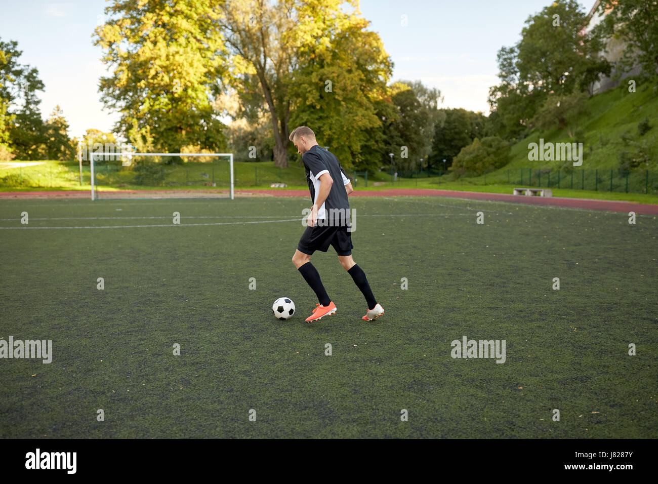 Fußballspieler mit Ball auf Fußballplatz spielen Stockfoto