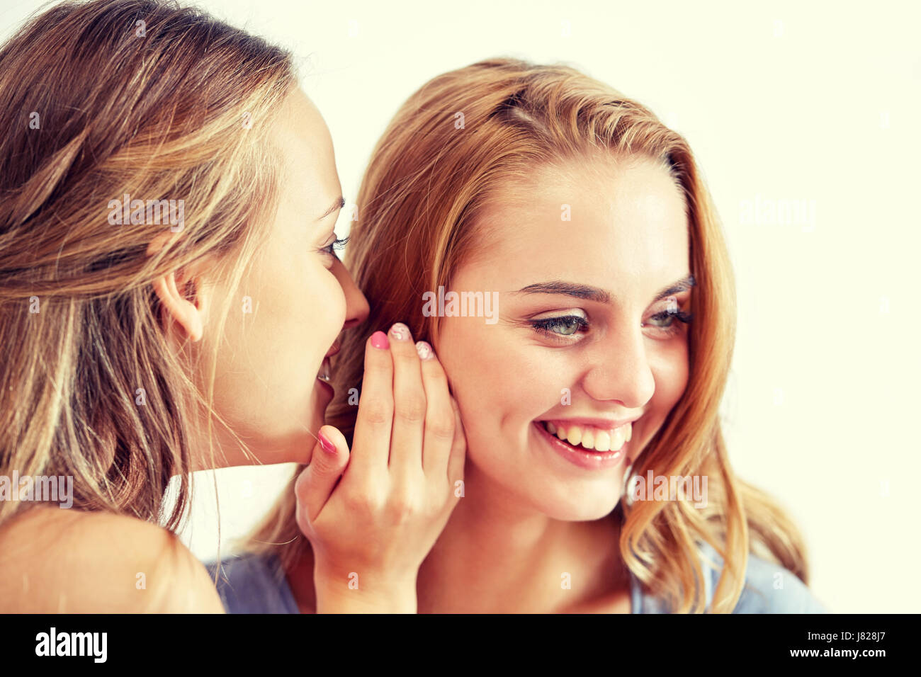 glückliche junge Frauen Flüstern Klatsch zu Hause Stockfoto