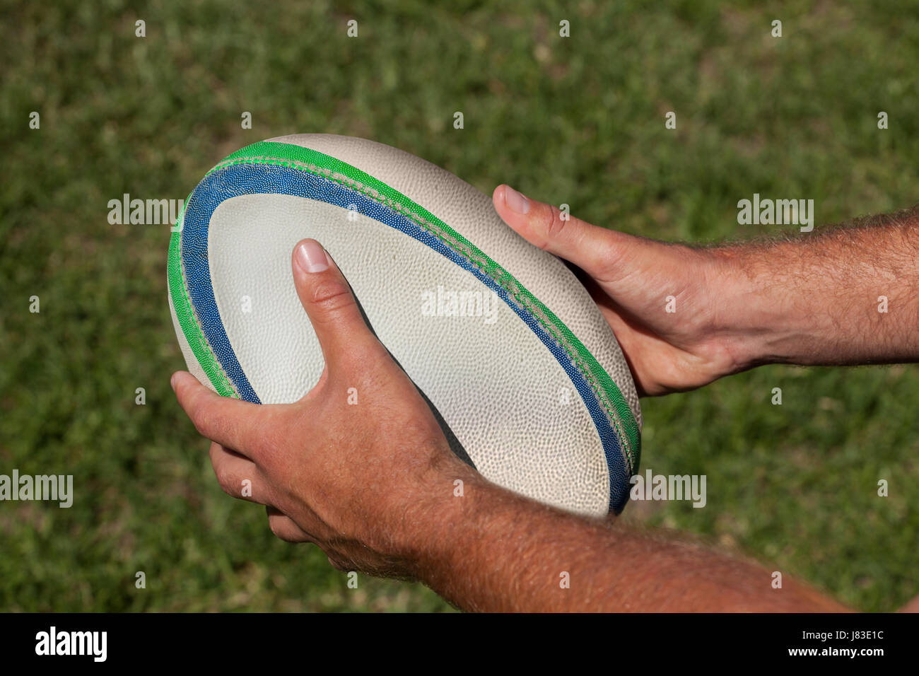 Erhöhte Ansicht des abgeschnittenen Hände halten Rugby-Ball im Feld Stockfoto