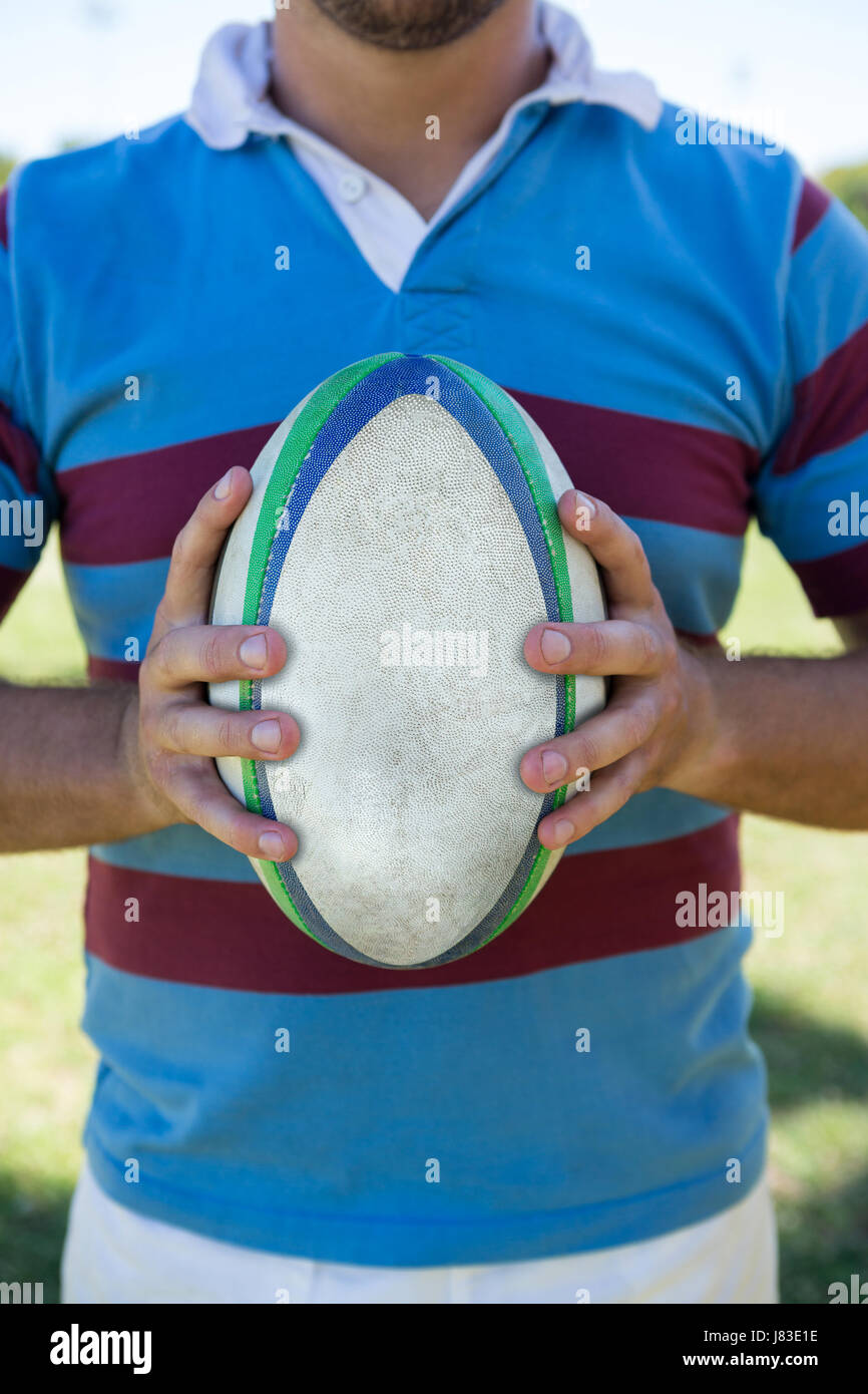 Mittelteil der Spieler, der Rugby-Ball stehend auf Feld Stockfoto