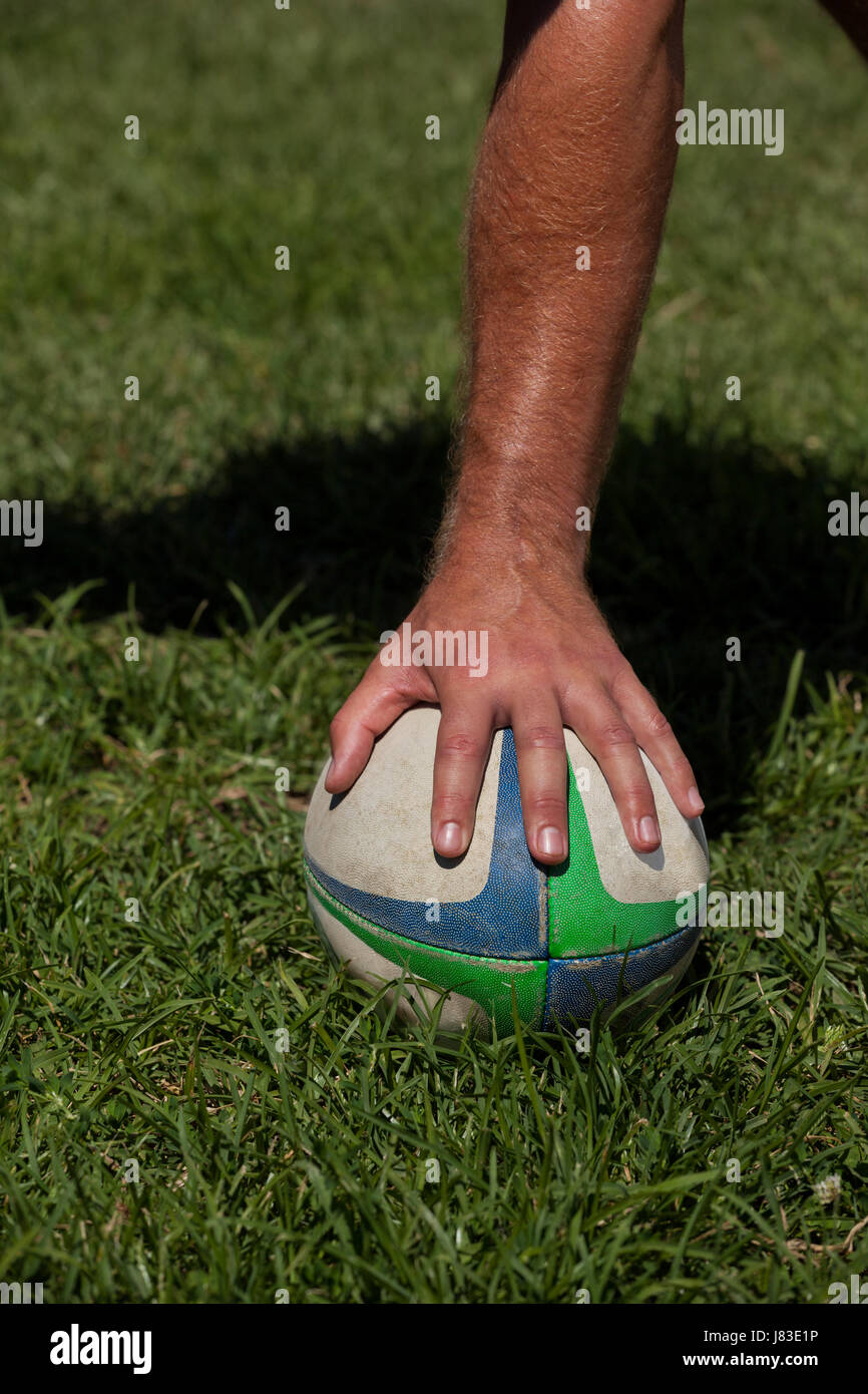 Beschnitten, Hand berühren Rugby-Ball auf Wiese Stockfoto