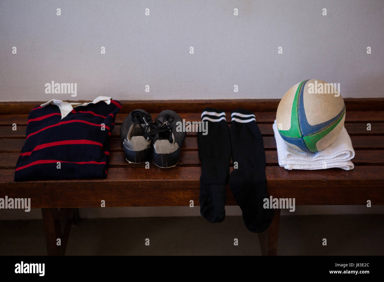 Vogelperspektive Blick auf Kleidung und Rugby ball auf Holzbank an Wand Stockfoto