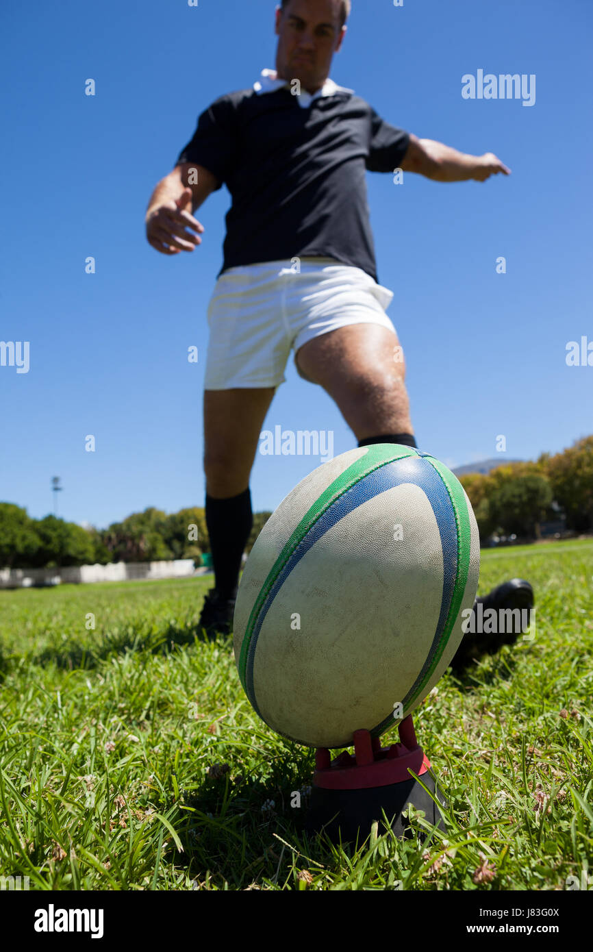 Niedrigen Winkel Blick auf Spieler treten Rugby-Ball auf Wiese Stockfoto
