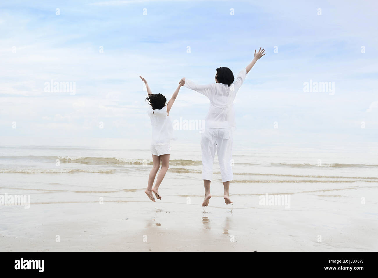 Entspannende asiatische Familie Zeit während der Sommerferien. Asiatische Mutter mit Tochter Hand in Hand, Spaß und springen am Strand. Stockfoto