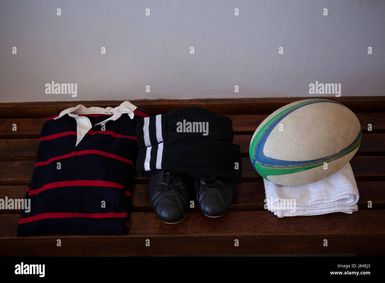 Erhöhte Ansicht des Rugby-Ball mit Kleidung und Schuhe auf Holzbank Stockfoto