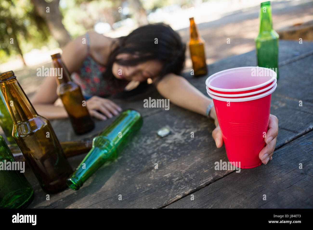 Betrunkene Frau schlafen auf dem Tisch und hält ein Glas Bier im park ...